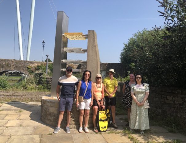 A summer walking tour group at Lancaster’s ‘Captured Africans’ sculpture, reflecting on the city’s heritage