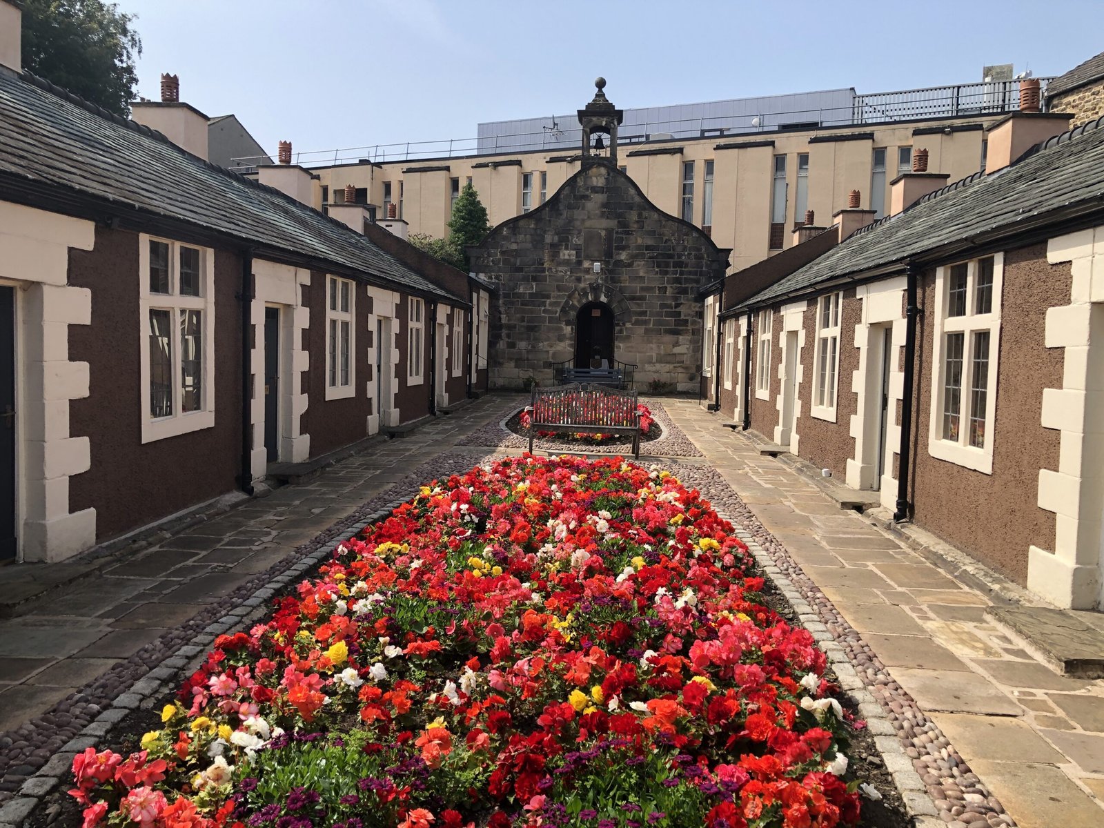 Historic Penny’s Hospital Almshouses, Lancaster, viewed through its courtyard with flowers, highlighting Georgian philanthropy and architecture